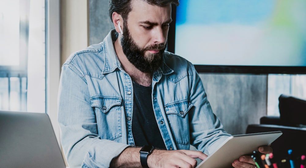 A bearded man looking at his tablet