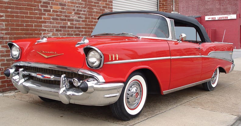 A classic red Chevrolet in front of a brick wall