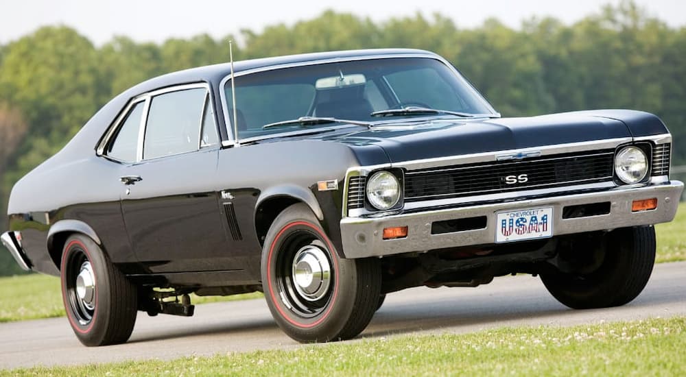 A black 1969 Chevy Nova is parked in the grass.