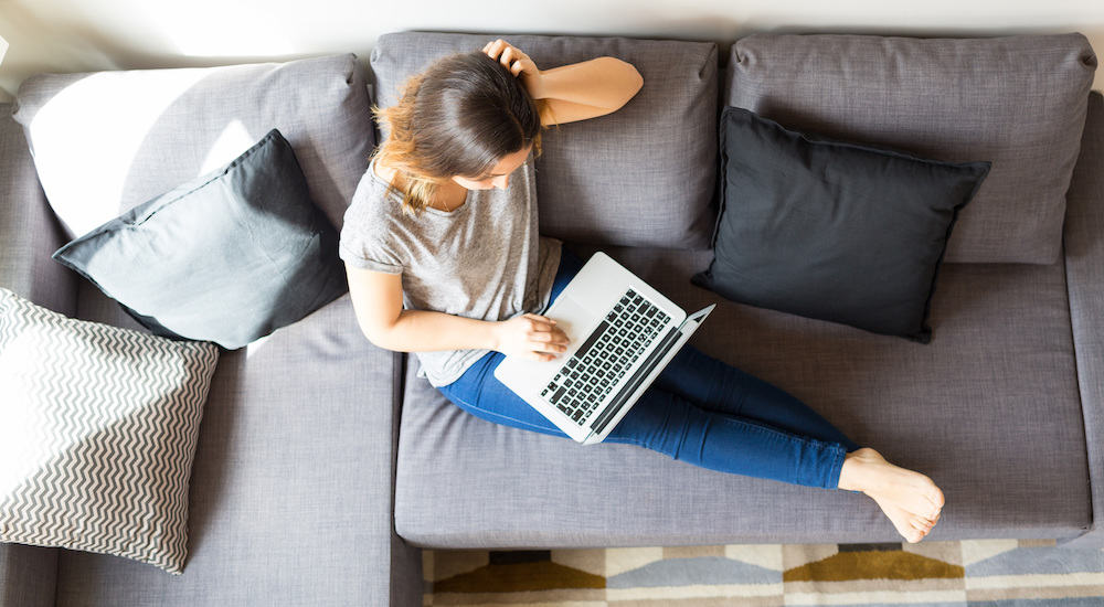 A woman sitting on her couch with a macbook pro