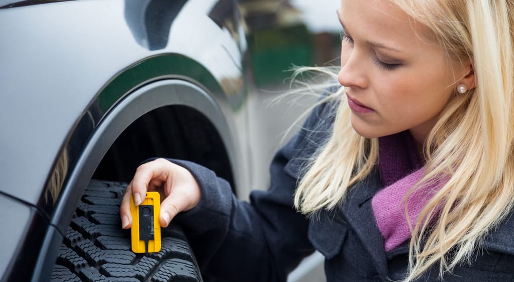 A woman measures the tread on her car tires