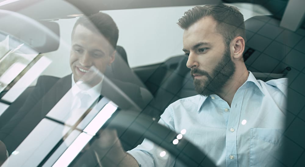 A customer and car salesman checking out the interior of the car