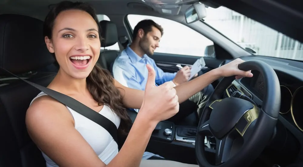 A woman and her husband giving a thumbs up in their new vehicle