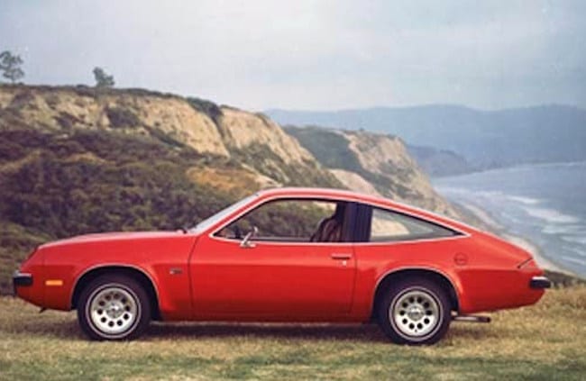 Chevy Monza in red parked on a rocky cliffside