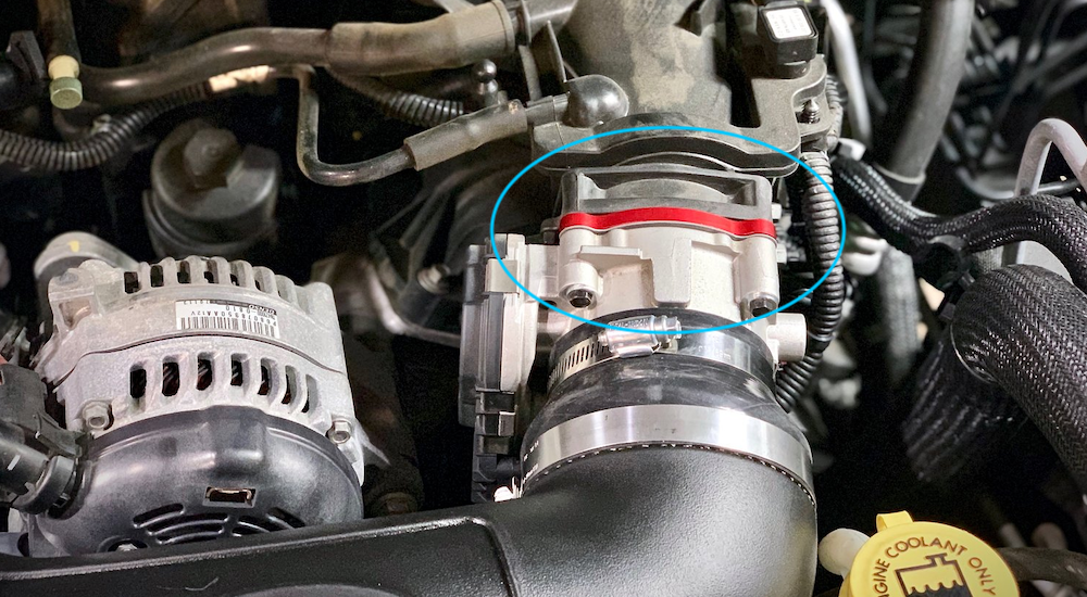 A throttle body spacer, circled in blue, is an aftermarket modification for a used Jeep Wrangler.