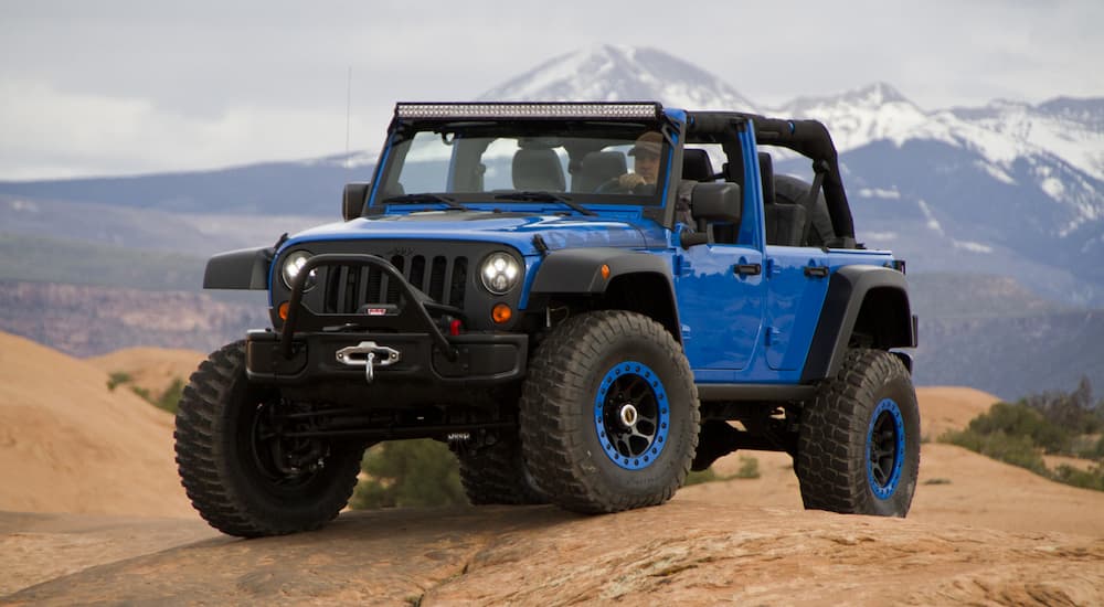 A 2014 Jeep Wrangler Max Performance edition from a Jeep Safari show is shown with mountains in the distance.