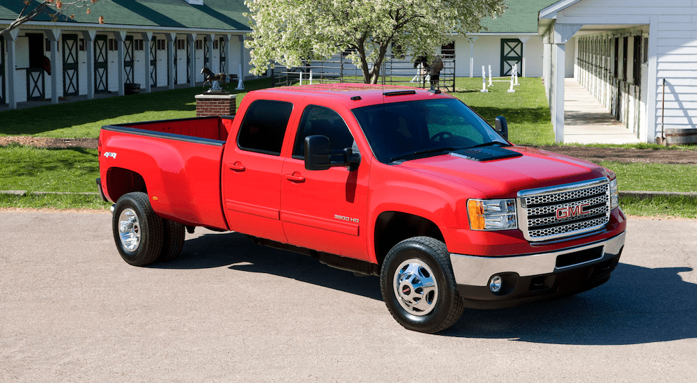 A red 2007 GMC Sierra 3500HD in front of a horse stable