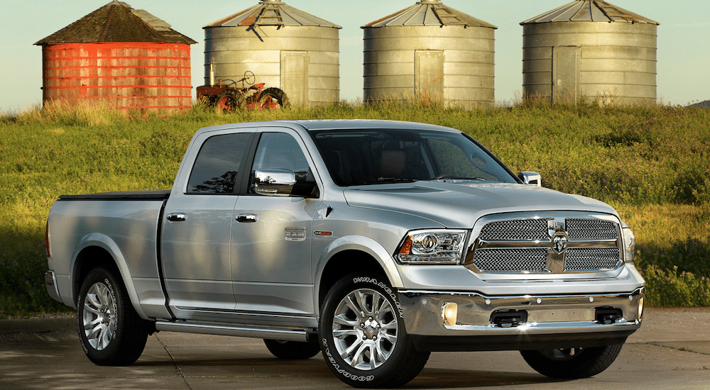 A silver 2014 Ram 1500 with grain silos in back