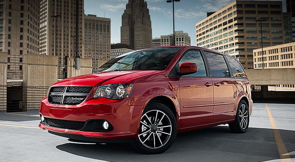 A red 2018 Dodge Grand Caravan is parked in front of city buildings.