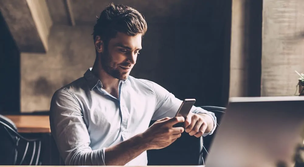 Guy looking at his phone and smiling in a dark room