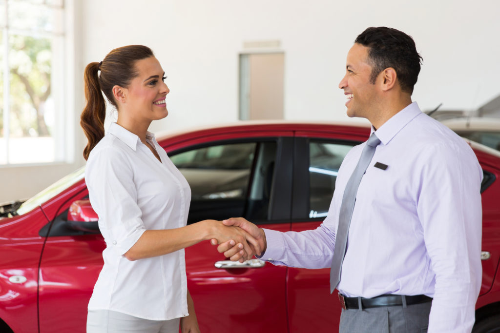 A woman shaking hands with her car salesman