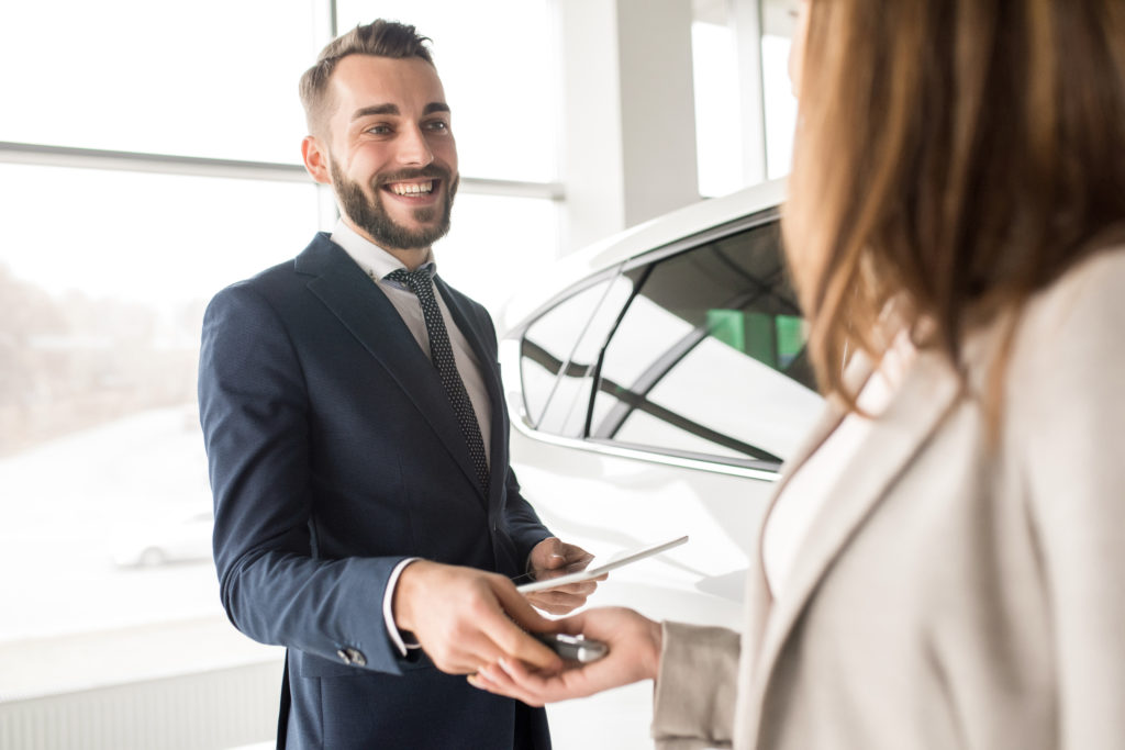 A smiling man handing over the keys to a new car