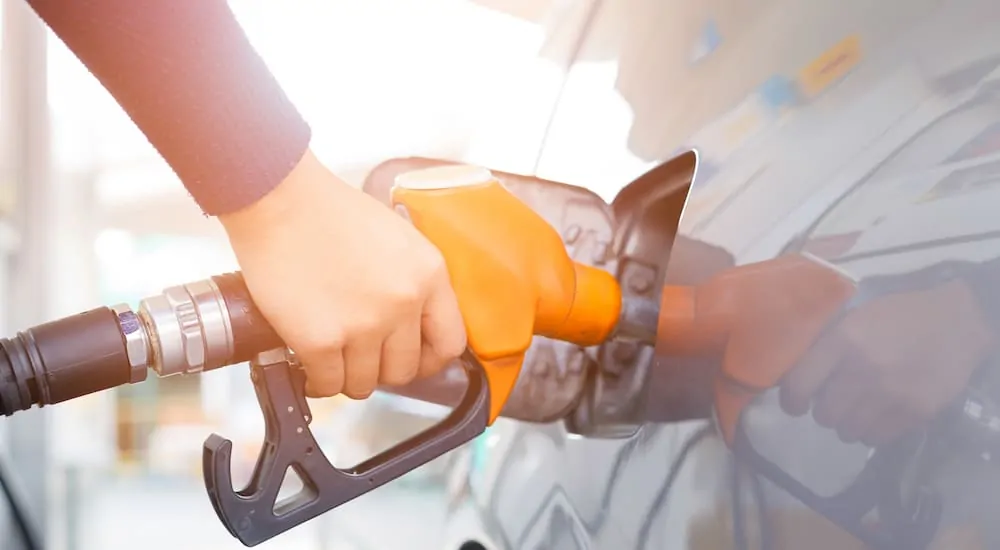 A woman's hand pumping gas with an orange pump