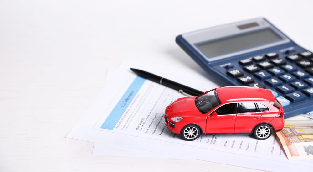 A toy car, money, documents and a calculator are on table.