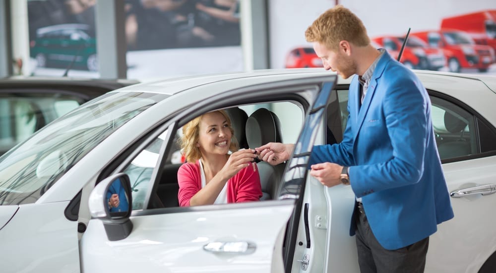 A buy here pay here dealer employee is with a female customer looking at a vehicle. 