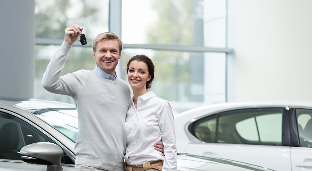 A couple is holding the keys to the car they bought at a buy here pay here dealer.