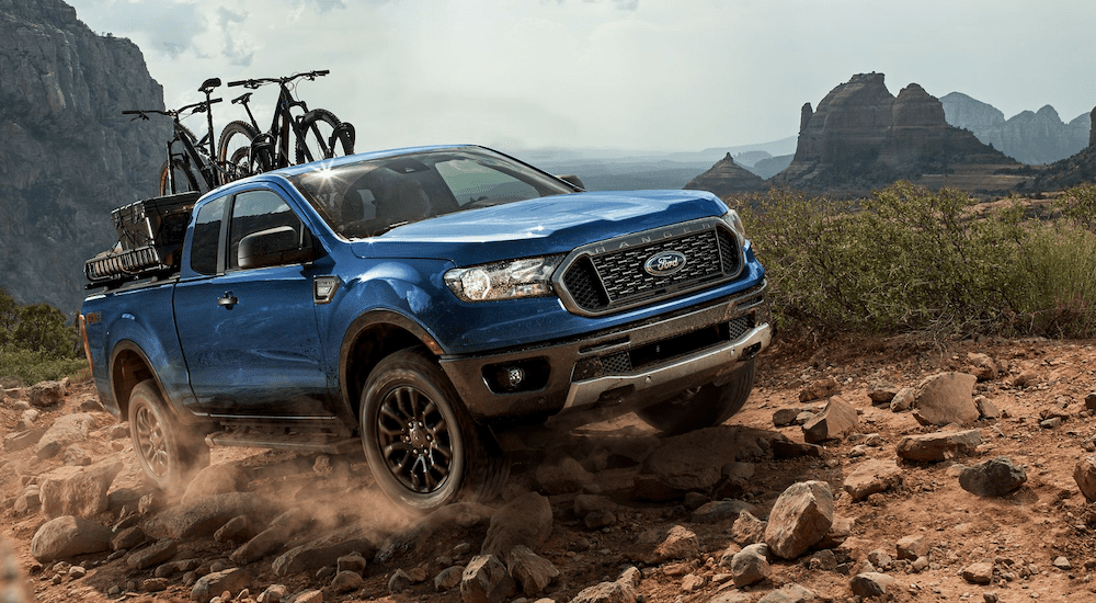 A blue 2019 Ford Ranger is offroading mountain trails with bikes in the bed.