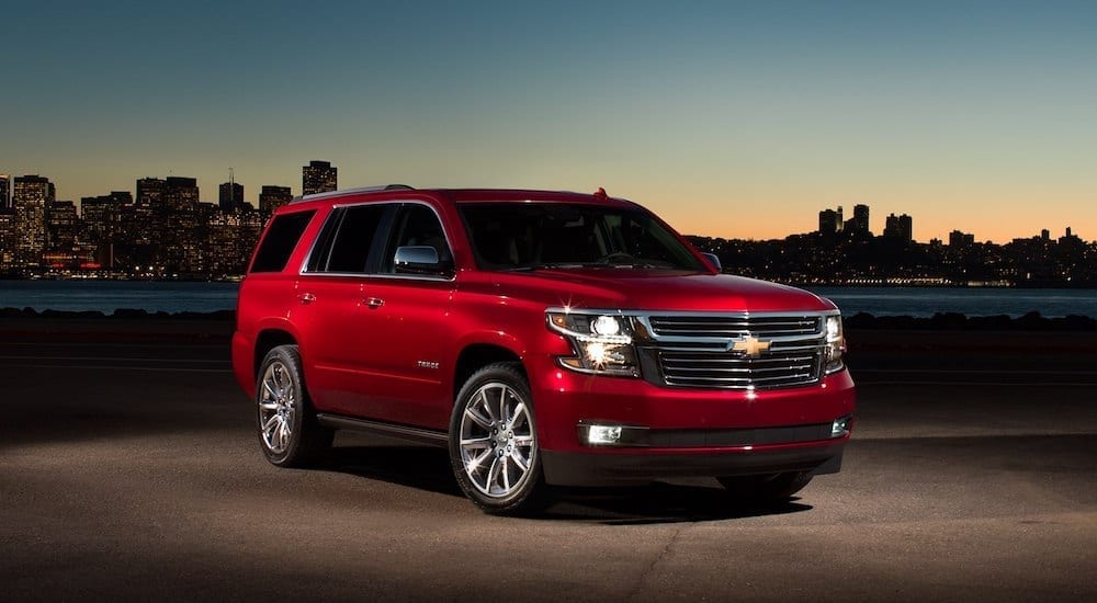 Red 2018 Chevrolet Tahoe in front of cityscape at dusk