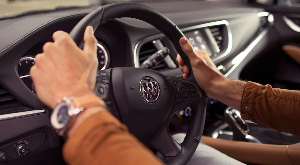 Closeup of 2019 Buick Enclave wheel and dashboard, arms holding wheel