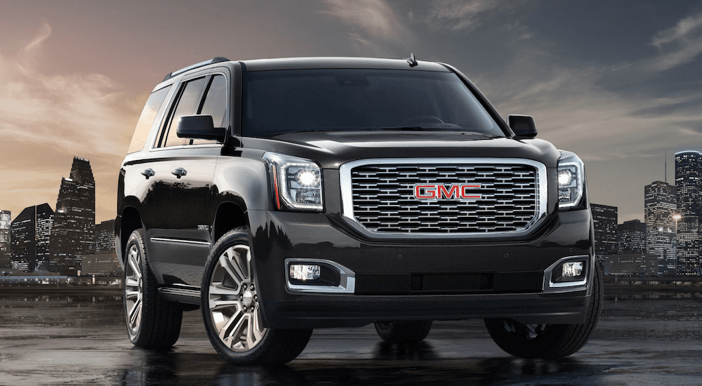 Black 2019 GMC Yukon Denali with cityscape in back at dusk