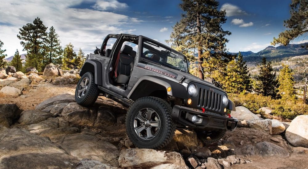 A gray Jeep Wrangler navigates a rocky trail