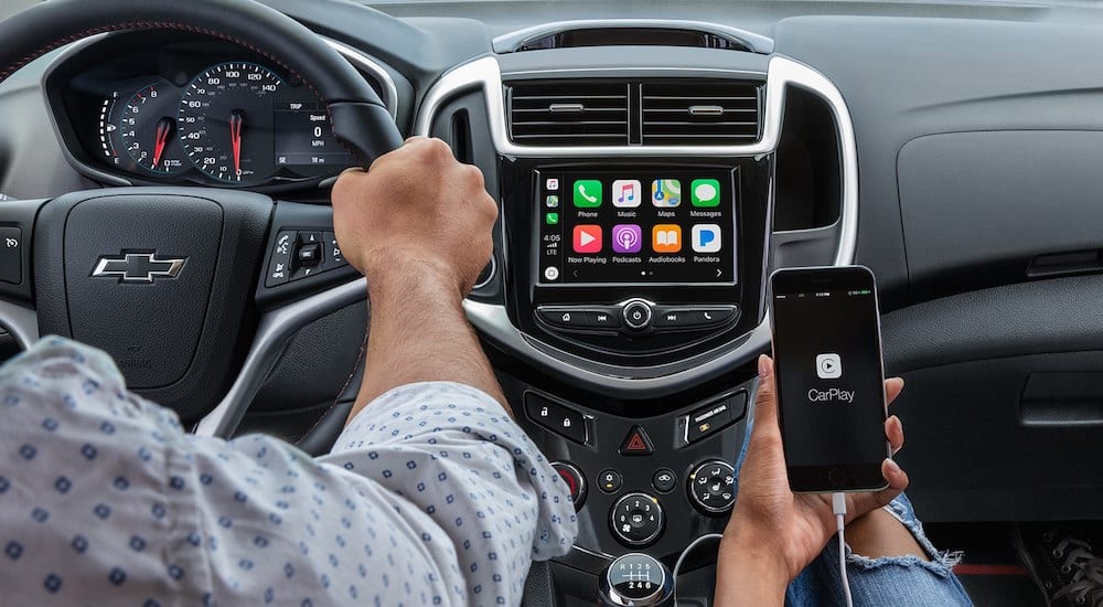 Black interior and infotainment screen of 2019 Chevy Sonic with smartphone connecting
