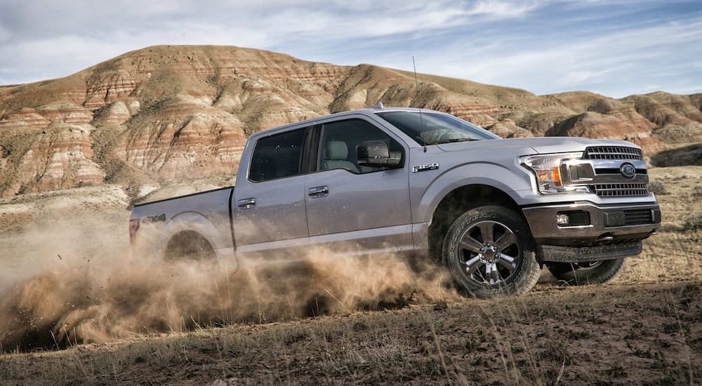 Silver 2019 Ford F150 driving on dirt road in mountains