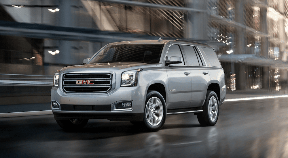 Silver 2019 GMC Yukon driving in city with out of focus building in back