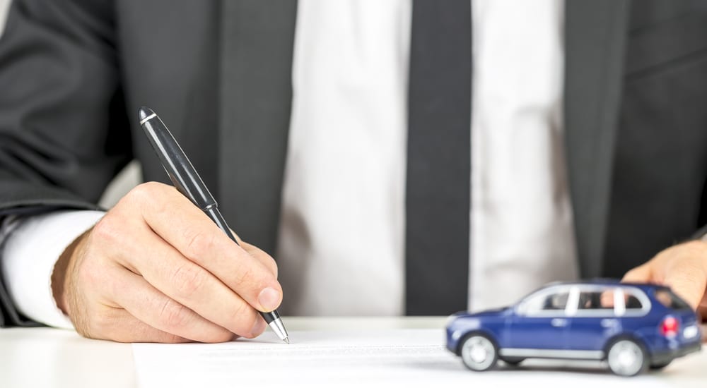 Closeup of man signing a contract of car sale.