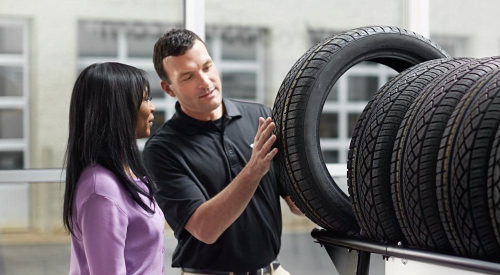 A technician helps a customer select new tires