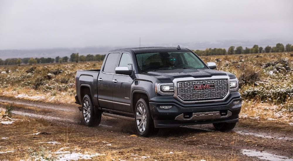 Black 2019 GMC Sierra Denali 2500HD driving in dirt field