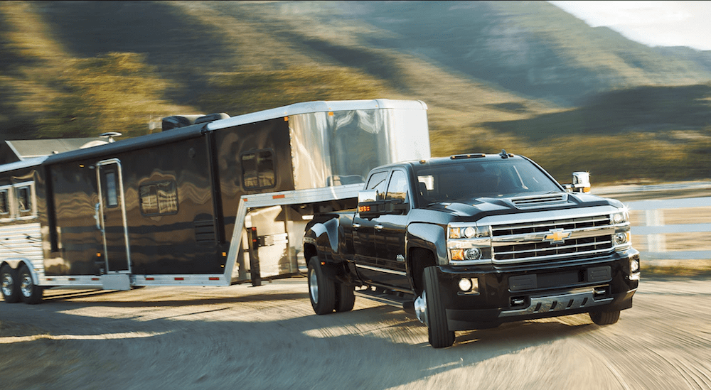 A black Chevy Silverado HD towing a large trailer