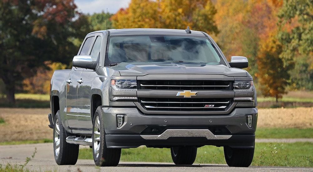 A gray 2017 Chevy Silverado with multicolored fall leaves in the background