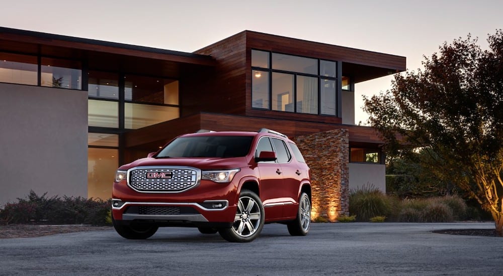 A red 2019 GMC Acadia Denali in front of a modern home
