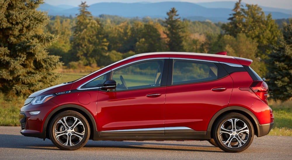 A red 2019 Chevrolet Bolt EV with trees and mountains in back