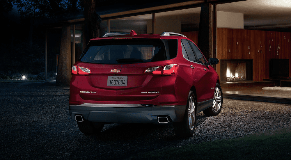 The back of a red 2019 Chevy Equinox in front of a house at night