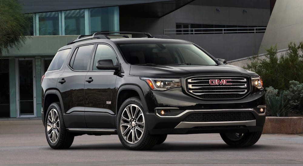 A black 2019 GMC Acadia All Terrain parked in front of a house