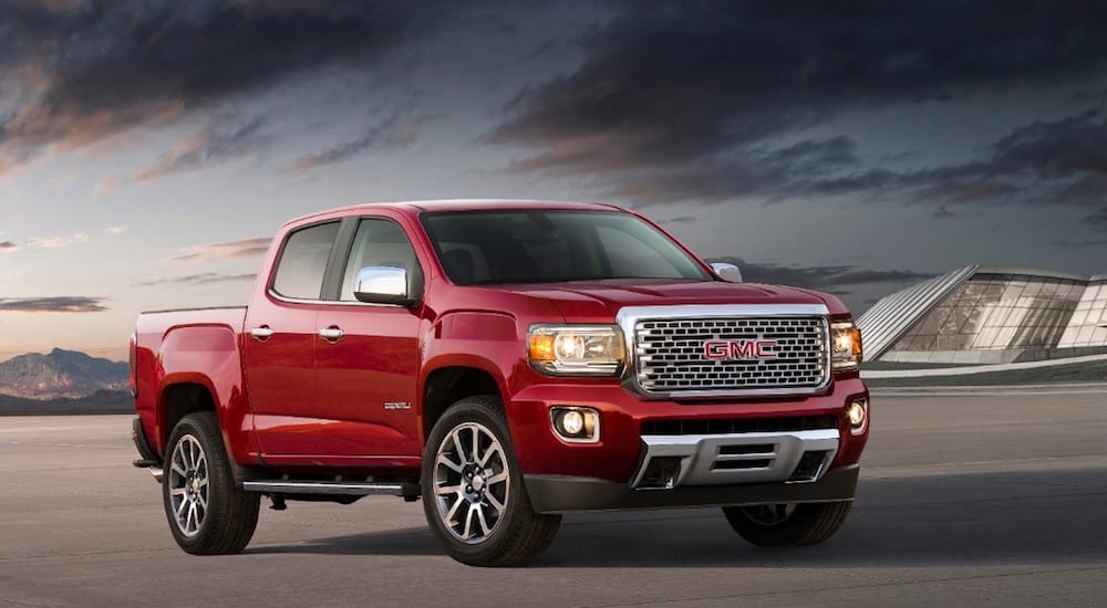 A red 2019 GMC Canyon Denali parked in front of a glass building