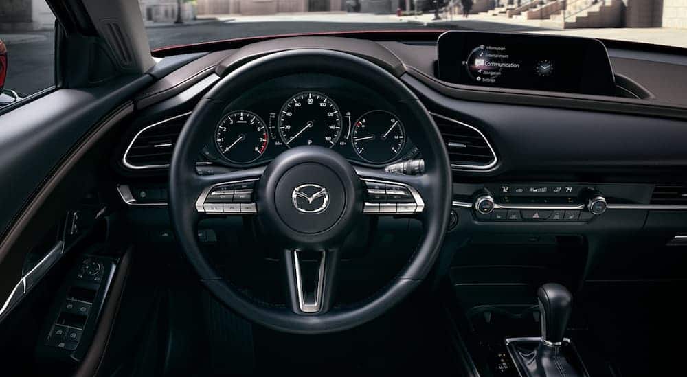 The black leather interior that's found in a 2020 CX-30 is shown with a drivers display and infotainment system. 