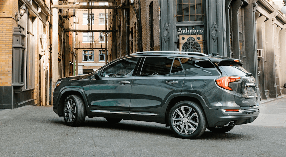 A grey 2019 GMC Terrain Denali edition is taking a corner on a tight city street. Its exterior styling is the winner when comparing the Comparing the 2019 GMC Terrain vs 2019 Honda CR-V.