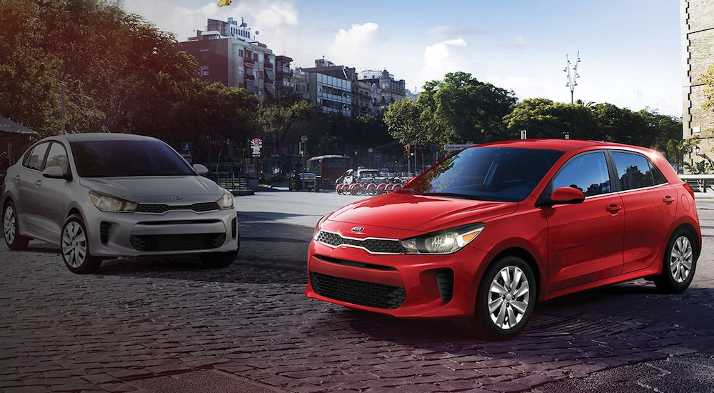 A red 2019 Kia Rio hatchback and silver Rio sedan in a city