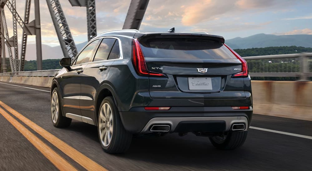 A grey 2019 Cadillac XT4 is driving over a bridge.