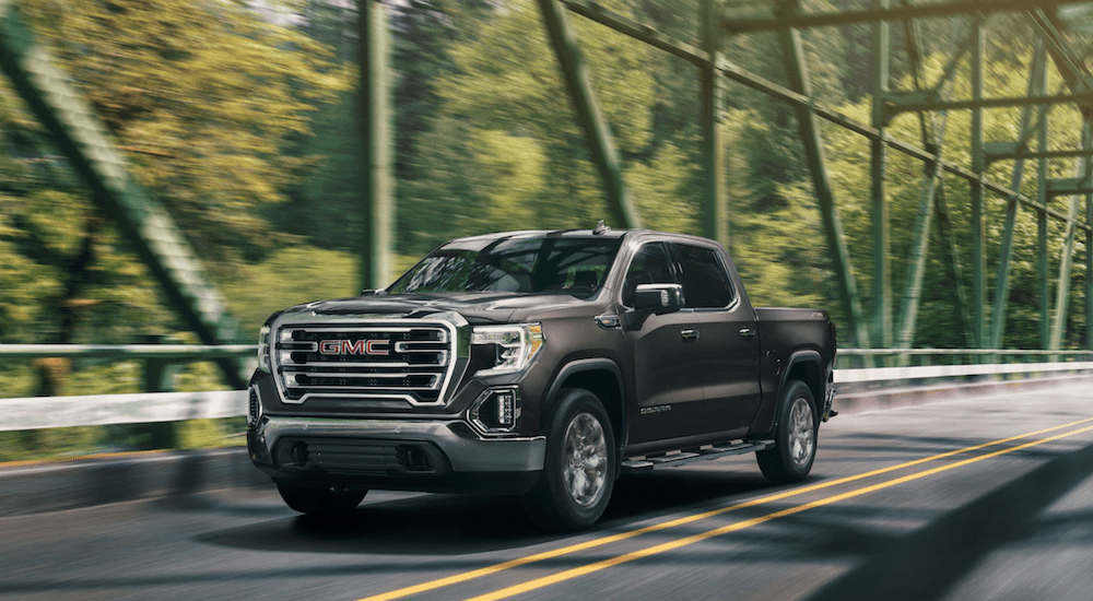 A brown 2019 GMC Sierra driving on a woodland bridge