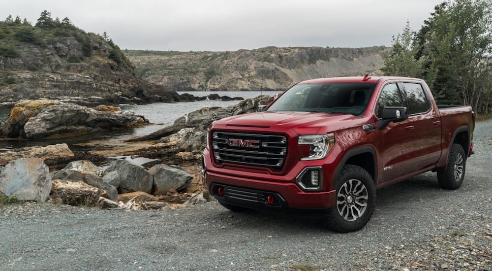 A red 2019 GMC Sierra AT4 in front of a lake and mountains