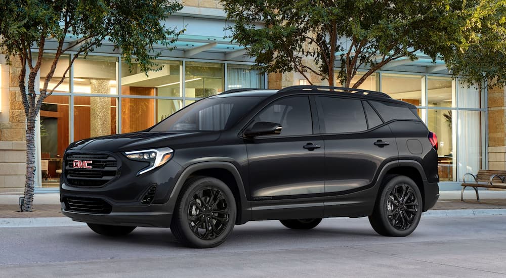 A Black Edition 2019 GMC Terrain is parked in front of a building with lots of glass. Compare performance when looking at the 2019 GMC Terrain vs 2019 Toyota RAV4.