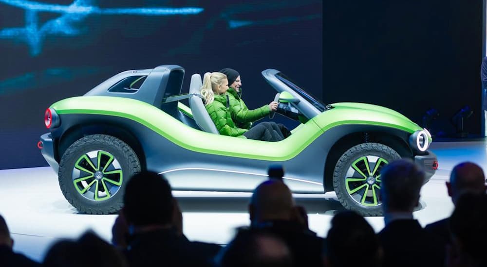 Two women are sitting in the green and black Volkswagen ID Buggy at the 2019 Geneva Motor Show Show VW Press Conference.