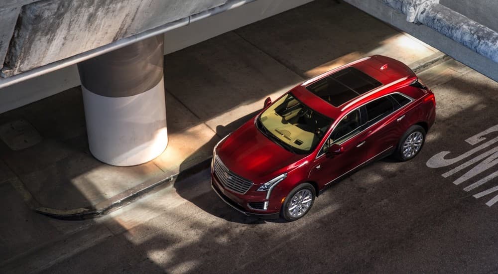 A red 2017 Cadillac XT5 is shown from above under an overpass.