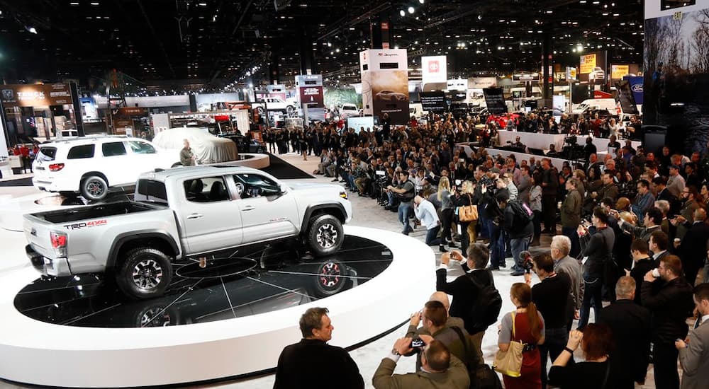 A crowd is gathered around the unveiling of a white 2020 Toyota Tacoma at the Chicago Auto Show.