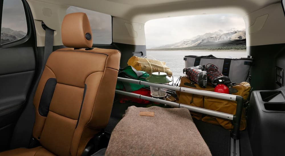 The tan and white interior of a 2019 GMC Acadia is shown with cargo in the back. Check out interior when comparing the 2019 GMC Acadia vs 2019 Ford Explorer.