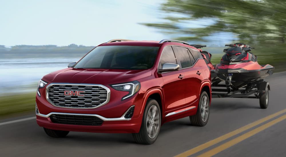 A red 2019 GMC Terrain Denali is towing red jet skis. Comparing towing and performance when looking at the 2019 GMC Terrain vs 2019 Jeep Cherokee.